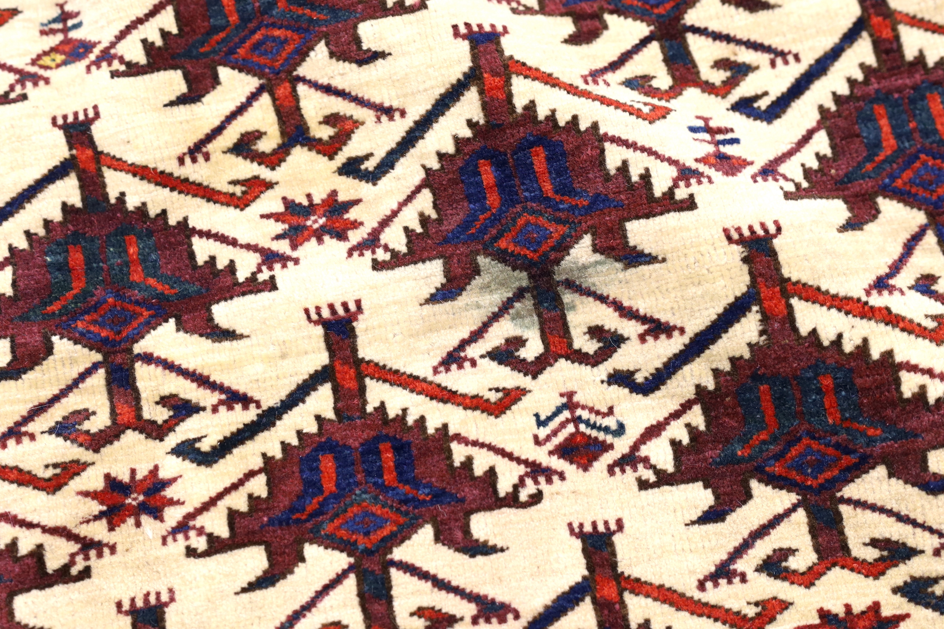 An antique Afghan arched panel woven with rows of stepped decoration on an ivory ground, width 150cm, depth 83cm